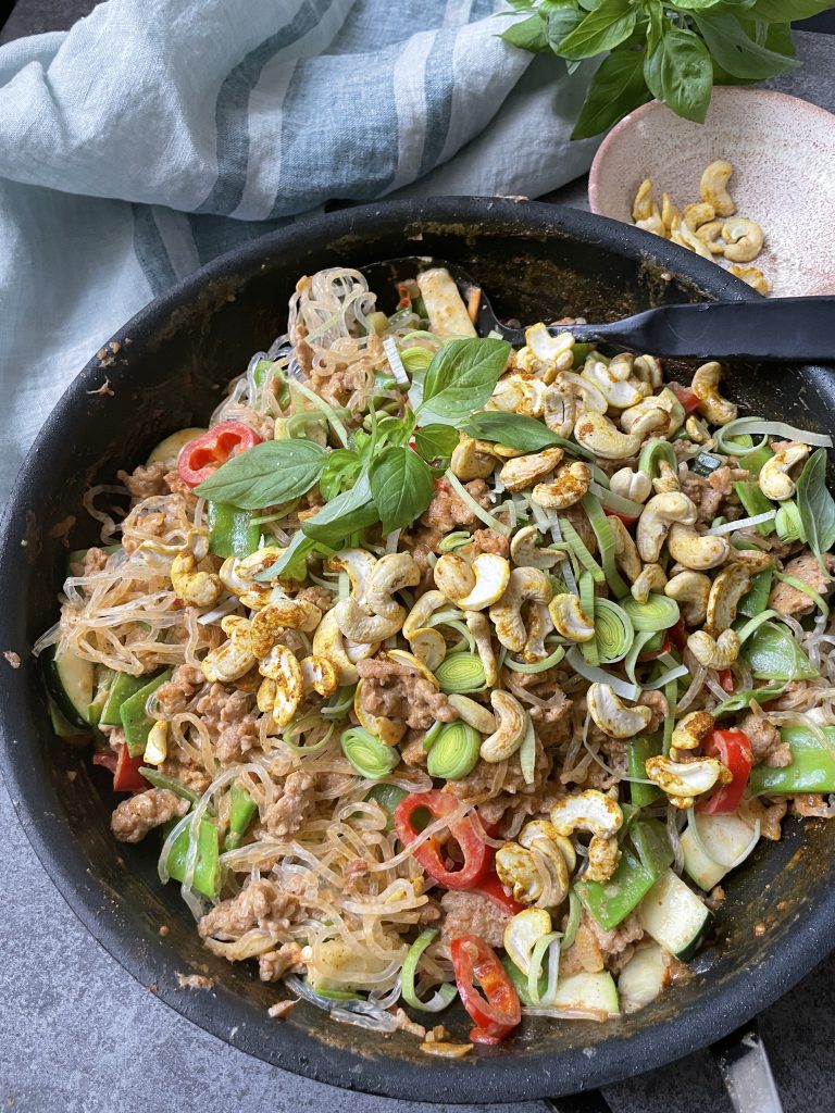 En stekpanna fylld med glasnudlar, sauterade grönsaker, köttfärs, körsbärstomater, cashewnötter, skivad salladslök och färsk basilika - en inbjudande rätt inspirerad av hälsosamma recept och kraften i functional foods.
