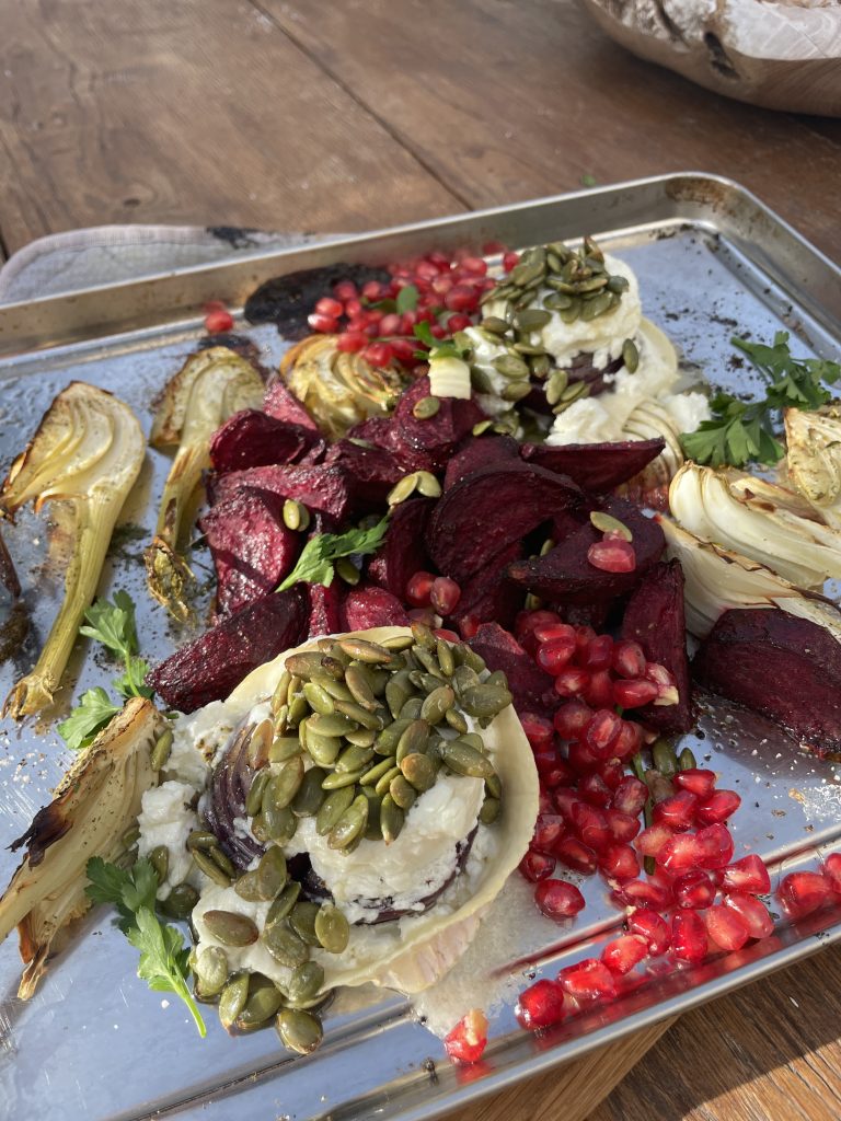 En metallbricka med rostad fänkål, rödbetor, vispad ost, pumpakärnor, granatäppelkärnor och färsk persilja på ett träbord - ett levande exempel på funktionell matta perfekt för den som söker hälsosamma recept.