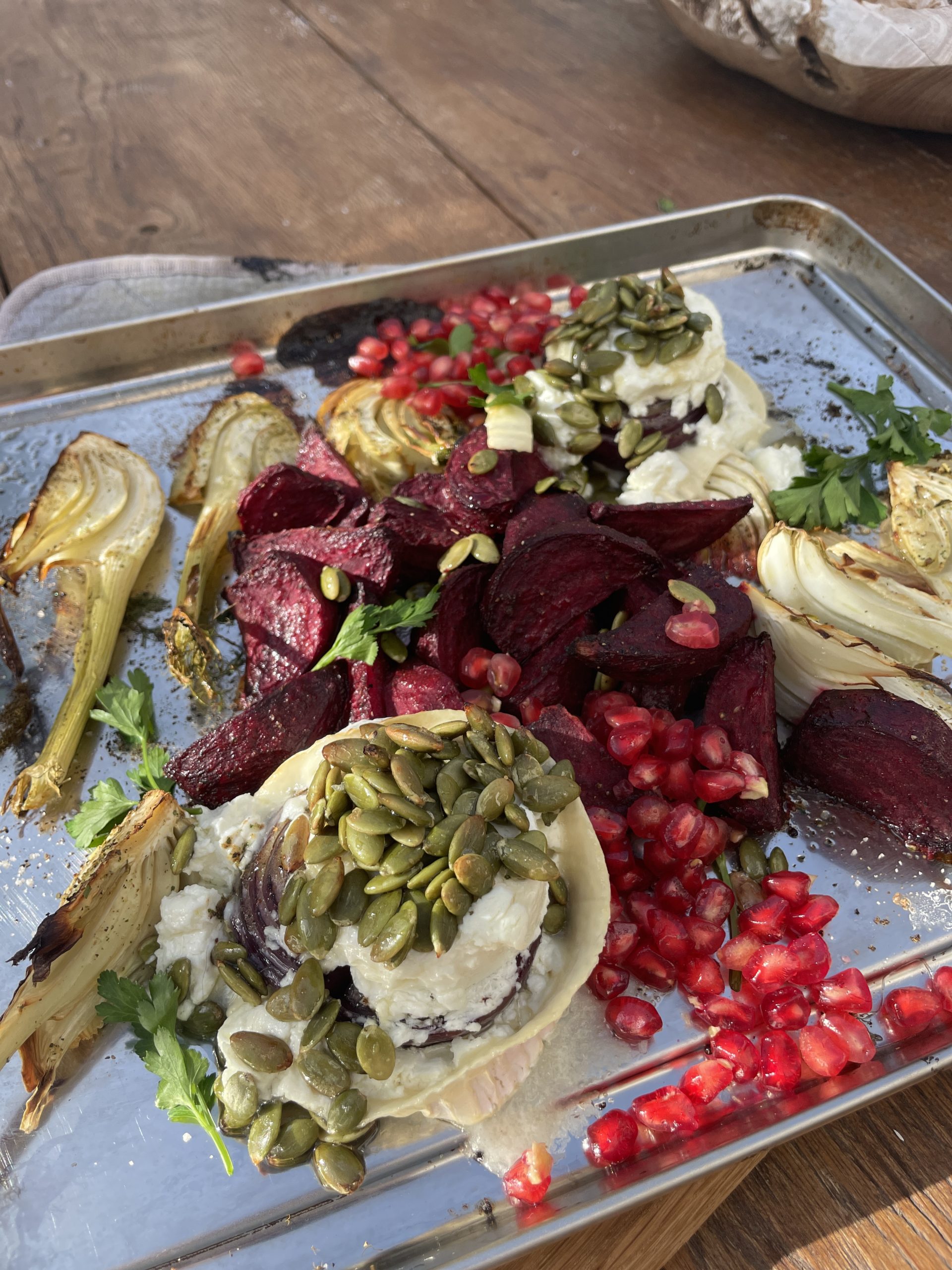 En metallbricka med rostad fänkål, rödbetor, vispad ost, pumpakärnor, granatäppelkärnor och färsk persilja på ett träbord - ett levande exempel på funktionell matta perfekt för den som söker hälsosamma recept.